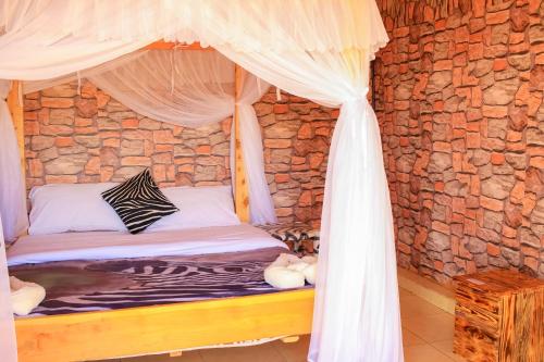 a bed in a room with a stone wall at Amanya Zebra 1-Bed Wigwam in Amboseli in Amboseli