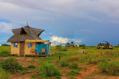 a small house with a thatched roof in a field at Amanya 1-Bed Zebra Tent in Amboseli