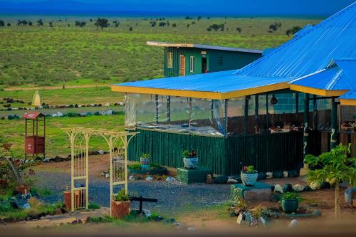 a building with a blue roof and a house at Amanya 1-Bed Zebra Tent in Amboseli