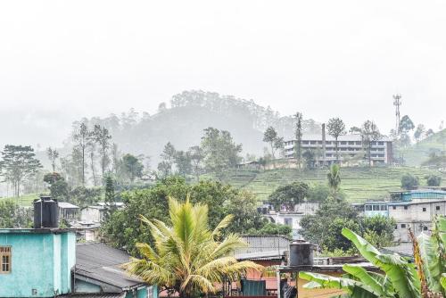 a city with houses and trees and a mountain at Archu Agam in Kotagala
