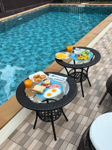 two tables with plates of food next to a swimming pool at BSK Bungalows in Lipa Noi