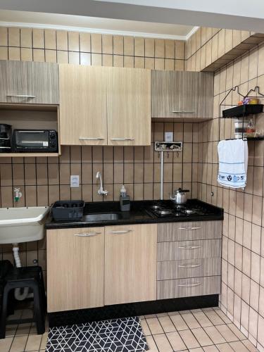 a kitchen with wooden cabinets and a sink at AP Abdon Central Temporada in Joinville