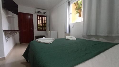 シャパダ・ドス・ギマランイスにあるPousada do Didi Chapada dos Guimaraes.の窓付きの白い部屋の緑のベッド
