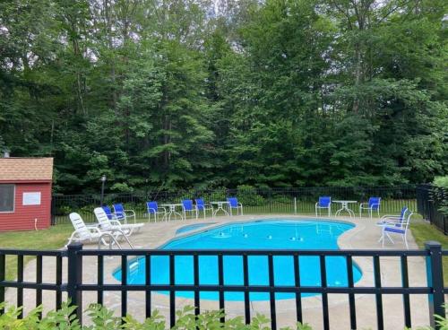 a swimming pool with blue chairs and chairs around it at Cozy Condo in the Woods (5 mins to Loon Mountain) in Lincoln