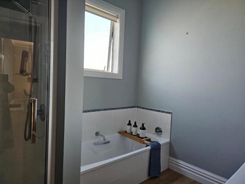 een badkamer met een bad en een raam bij Aspiring Villa Apartment in Christchurch