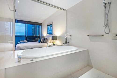 uma casa de banho branca com uma banheira e uma cama em Circle on Cavill - Sub Penthouse - Self Contained, Privately Managed em Gold Coast