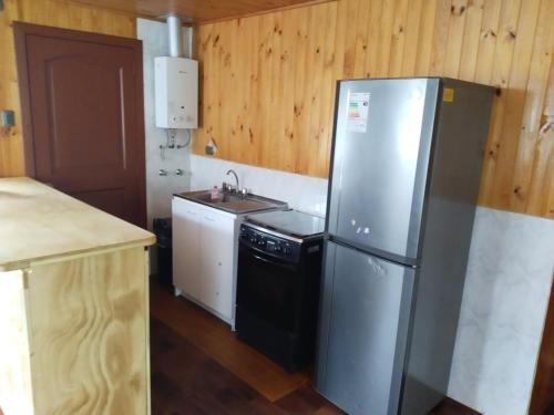 una cucina con frigorifero in acciaio inossidabile e lavandino di Cabaña La pincoya ad Achao