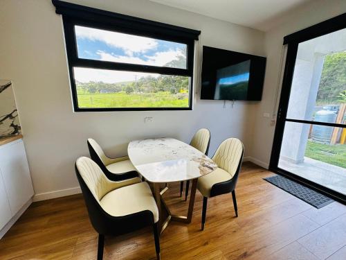 a dining room with a table and chairs and a window at Apollo Dream Suites in Apollo Bay