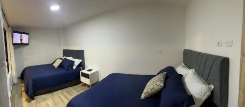 1 dormitorio con 2 camas, mantas y almohadas azules en Apartasuites Bogotá 53 cerca al aeropuerto 01, en Bogotá