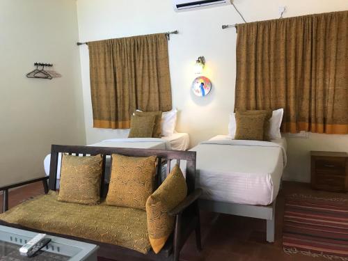 a hotel room with two beds and a couch at Marari Dreamz Homestay in Mararikulam
