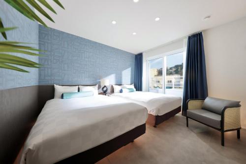 um quarto de hotel com duas camas e uma cadeira em クリスタルヴィラ白良浜ビーチ em Kanayama