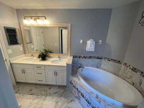 a bathroom with a tub and two sinks and a mirror at Beautiful Modern 3 BR House - Downtown Orlando in Orlando