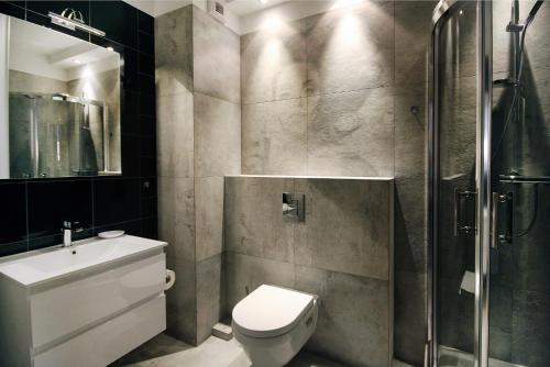 a bathroom with a toilet sink and a shower at Livin Apartments Santocka in Szczecin
