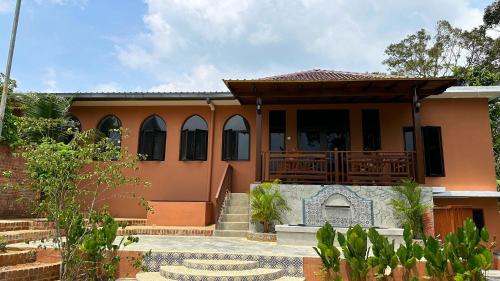 an orange house with a porch and a fireplace at The Manzil Janda Baik in Bentong