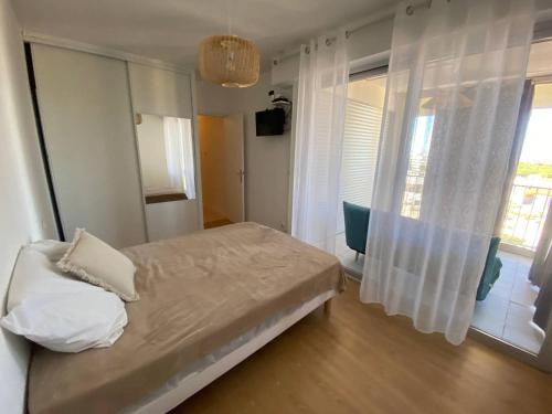 une chambre avec un lit et une grande fenêtre dans l'établissement Duplex T3 avec Clim, Parking et Wifi - 6 Pers, Le Barcarès - FR-1-81-606, au Barcarès