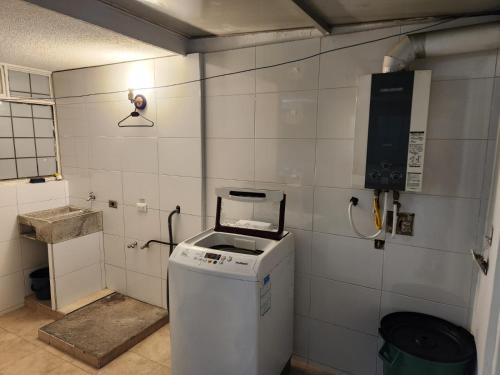 uma pequena casa de banho com uma máquina de lavar roupa e um telefone em Casa Chimenea a 5 minutos del Aeropuerto em Bogotá