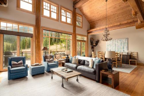 a living room with blue furniture and windows at Penthouse 3 by Moonlight Basin Lodging in Big Sky
