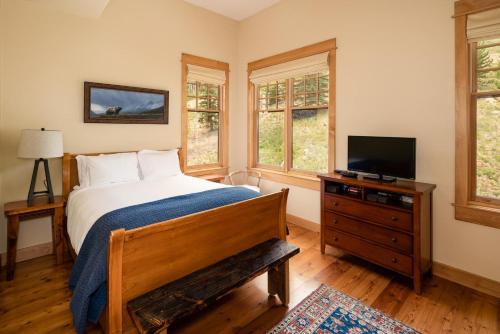 a bedroom with a bed and a tv and windows at Penthouse 3 by Moonlight Basin Lodging in Big Sky