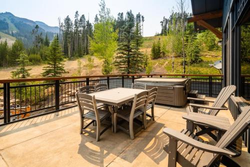 a deck with a table and chairs and a grill at Penthouse 3 by Moonlight Basin Lodging in Big Sky