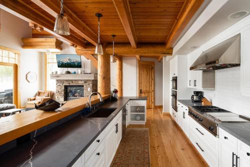 a large kitchen with white cabinets and wooden ceilings at Penthouse 1 by Moonlight Basin Lodging in Big Sky