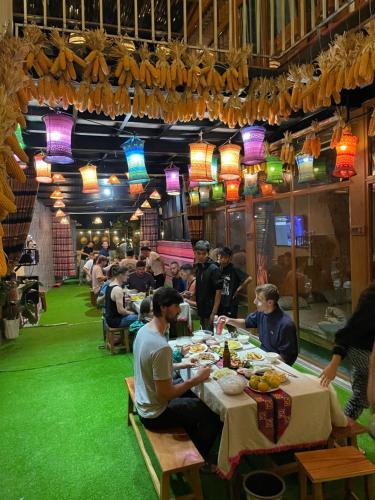 een groep mensen die aan een tafel eten bij Pura Homestay in Na Thôn