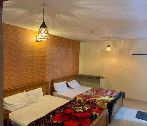 two beds in a small room with two lights at Cloudsmisty kodai in Kodaikānāl
