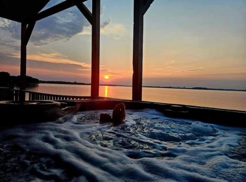 a hot tub with the sunset in the background at Lake Front Lake House Paradise! in Pittsburg