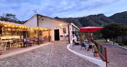 a restaurant with tables and chairs and a red umbrella at Hotel Cerro Fuerte in Sopó