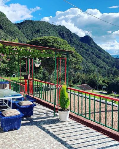 a deck with a table and chairs and mountains at Hotel Cerro Fuerte in Sopó