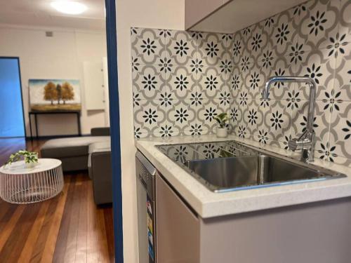 Il comprend une cuisine avec un évier et un salon. dans l'établissement 3 Bedroom Cozy Stay 5km CBD, à Sydney