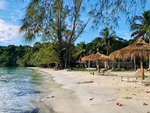 コタキエフ島にあるThe Last Point Koh Takievの藁傘と水を備えたビーチ