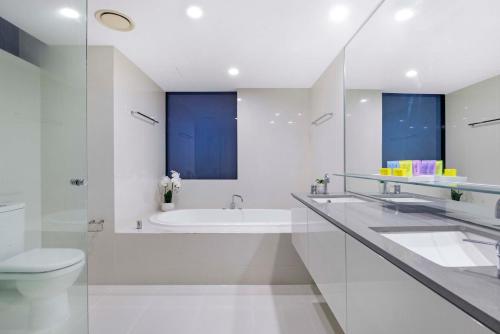 een witte badkamer met een bad en een toilet bij Pool View, Low Floor Apartment at Circle on Cavill - Wow Stay in Gold Coast