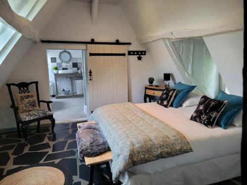 ein Schlafzimmer mit einem großen Bett und einem Stuhl in der Unterkunft Gîte de charme, bord de Loire Ma Maison Angevine in Le Thoureil
