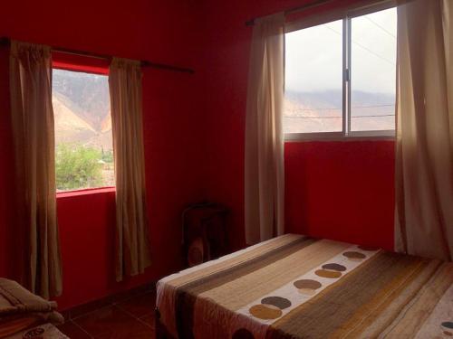 Dormitorio rojo con cama y ventana en Maimara Host en Maimará