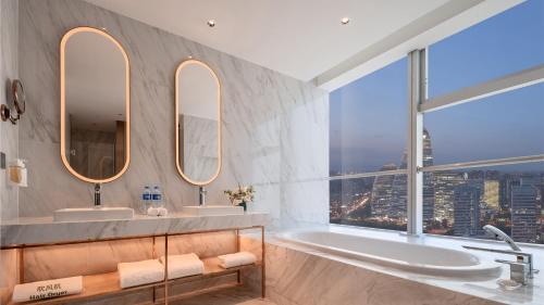 a bathroom with two sinks and a tub with two mirrors at Holiday Inn Beijing Focus Square by IHG in Beijing