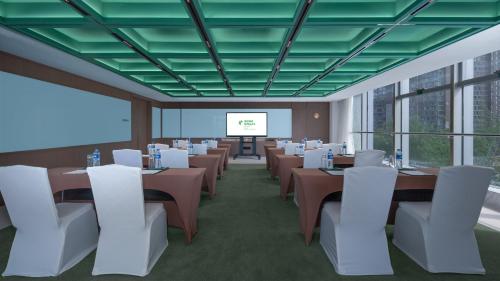 a conference room with tables and white chairs and a screen at Holiday Inn Beijing Focus Square by IHG in Beijing