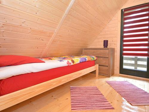 a bedroom with a bed in a log cabin at Comfortable holiday house with a garden, D bki in Dąbki
