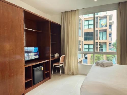 um quarto com uma cama, uma televisão e uma janela em Chalong inn Phuket em Chalong
