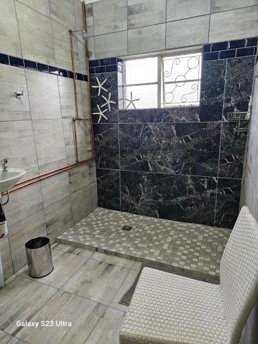 een badkamer met een douche, een bank en een wastafel bij The Witch's Inn in Philippolis