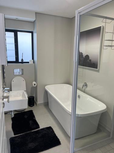 La salle de bains blanche est pourvue d'une baignoire et d'un lavabo. dans l'établissement Flat 2 Block 15 Bellamare, à Port Elizabeth