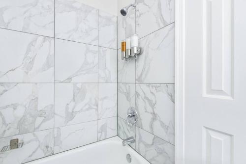 y baño con ducha y azulejos de mármol blanco. en The BEST Gorgeous & Luxurious Home Walk to Metro en Arlington