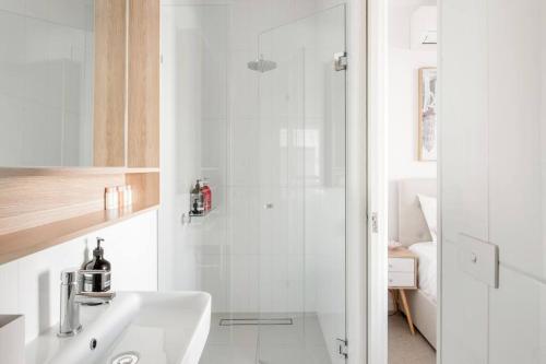 a white bathroom with a shower and a sink at Perfect Port Melbourne Townhouse in Melbourne