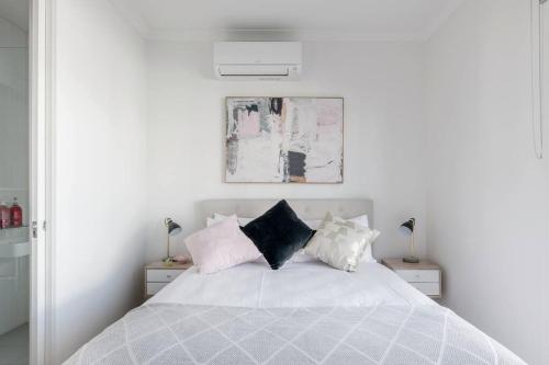 a white bedroom with a white bed with pillows at Perfect Port Melbourne Townhouse in Melbourne