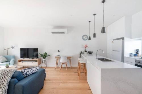 a living room with a blue couch and a kitchen at Perfect Port Melbourne Townhouse in Melbourne