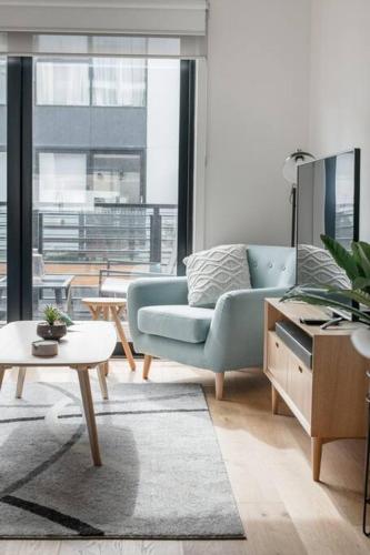 a living room with a blue couch and a large window at Perfect Port Melbourne Townhouse in Melbourne