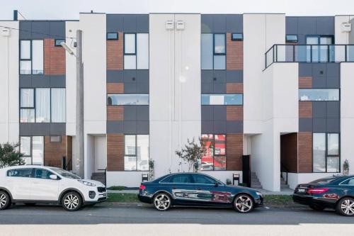 three cars parked in a parking lot in front of a building at Perfect Port Melbourne Townhouse in Melbourne