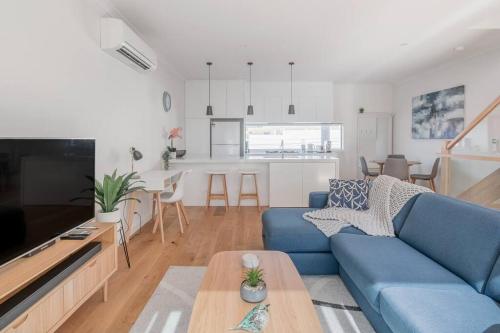 a living room with a blue couch and a table at Perfect Port Melbourne Townhouse in Melbourne