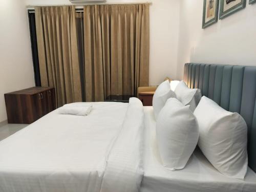 a bedroom with a white bed with white pillows at The Hoften Elite 32 Avenue, Sector 15, Gurugram in Gurgaon