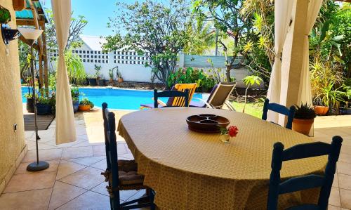 einen Tisch und Stühle mit einem Tisch und einem Pool in der Unterkunft Ti case fleurie * Piscine * Jardin tropical in Saint-Leu