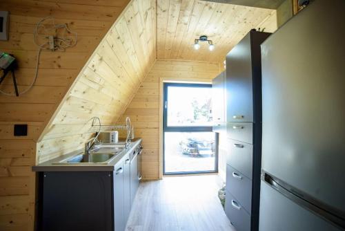 an attic kitchen with a sink and a window at Cabana din Vale Arieseni Apuseni in Arieşeni